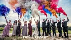 Люди на свадьбе держат в руке цветной дым разных цветов